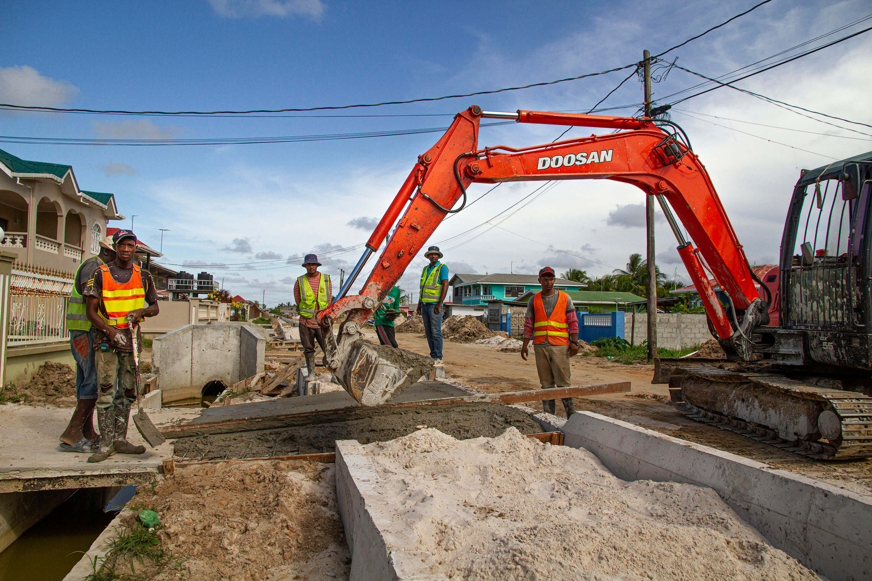 Construction workers and excavator on a Guyana project site